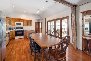 Una cocina amplia con armarios de madera, una mesa de comedor con sillas y un gran ventanal.