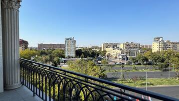 A balcony with a view of a cityscape, including buildings and a parking area.