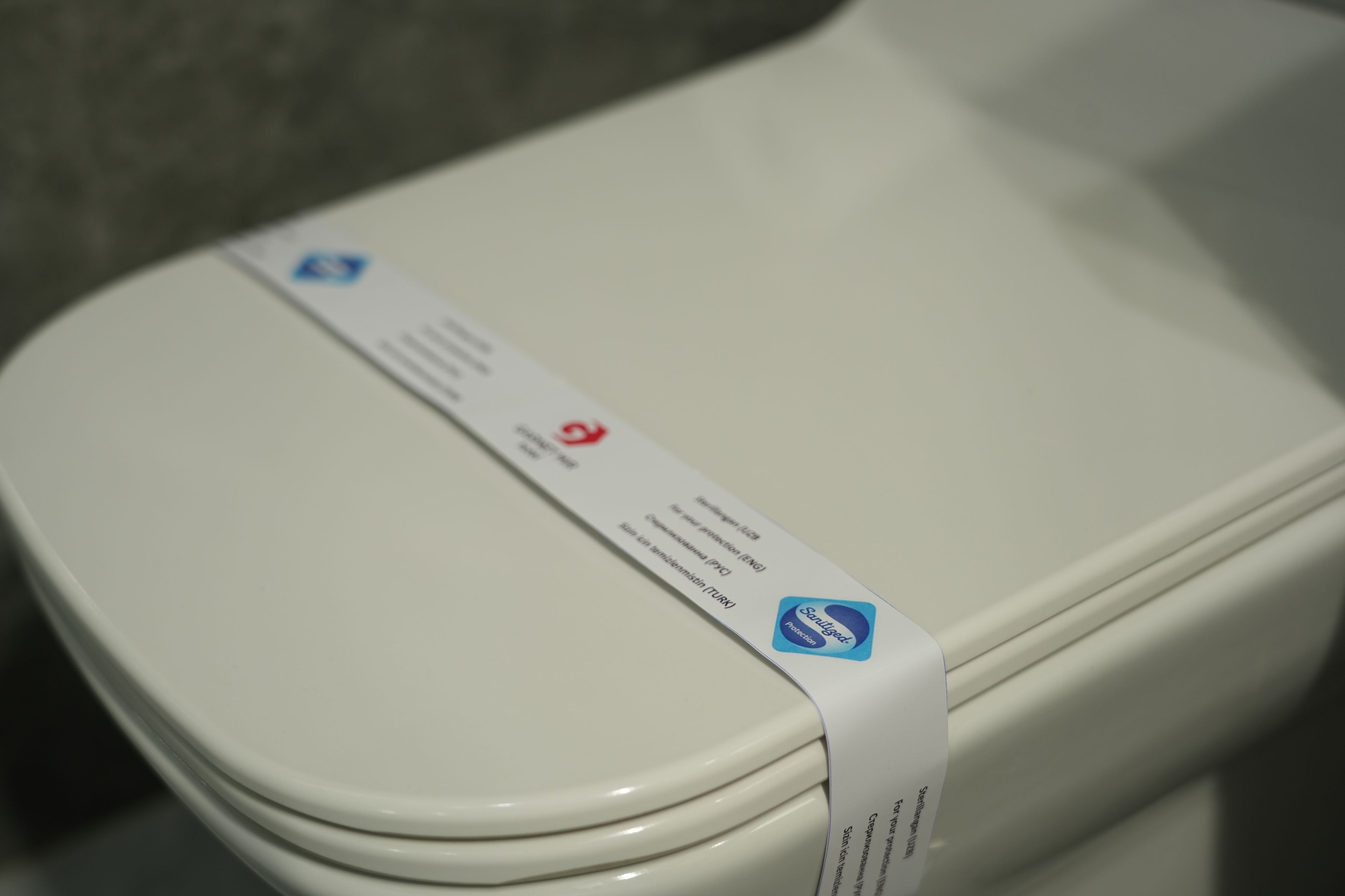 A toilet with a white lid and a label attached to it.