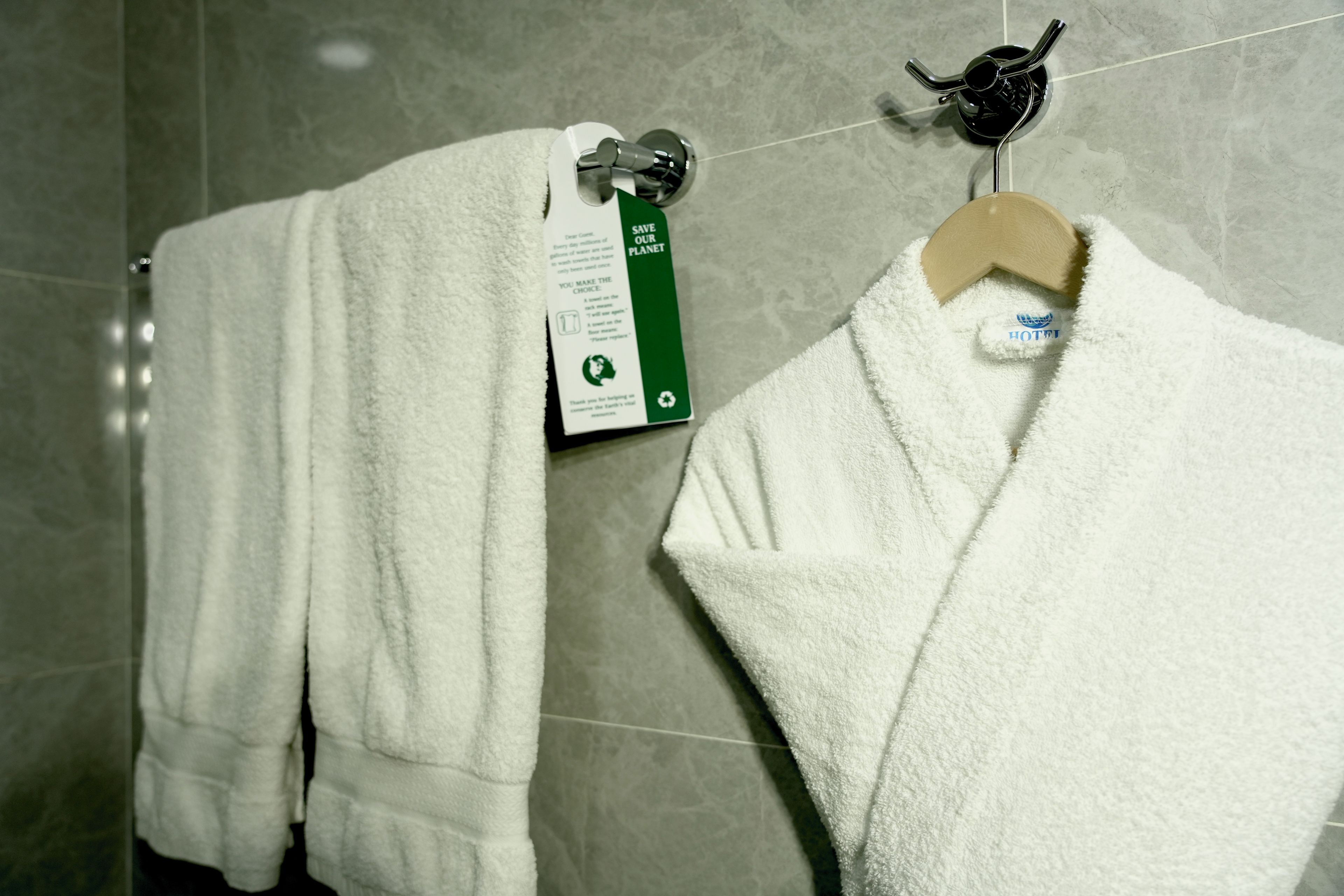 A bathroom with a white towel hanging on a rack and a towel hanging on a hook.