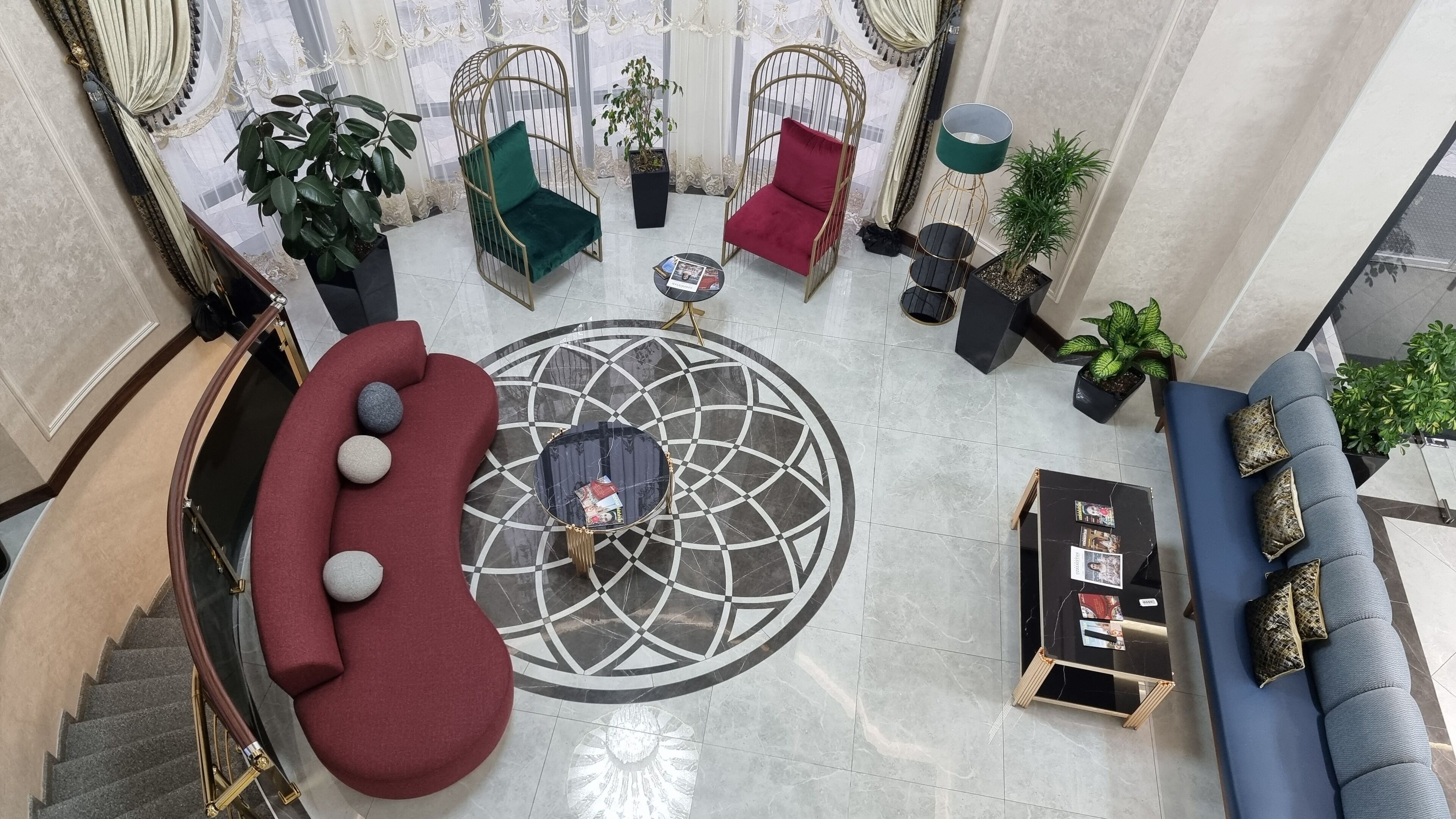 A spacious lobby with a central circular patterned floor, a red sofa, a blue sofa, and a black coffee table with magazines.