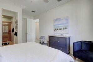Une chambre à coucher avec un grand lit, une commode, une chaise et un tableau accroché au mur.