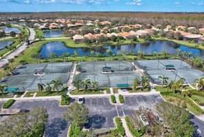 An aerial view of a residential area with multiple ponds, a sports complex, and a parking lot.