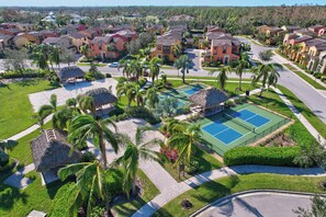 A residential area with houses, a tennis court, and palm trees.