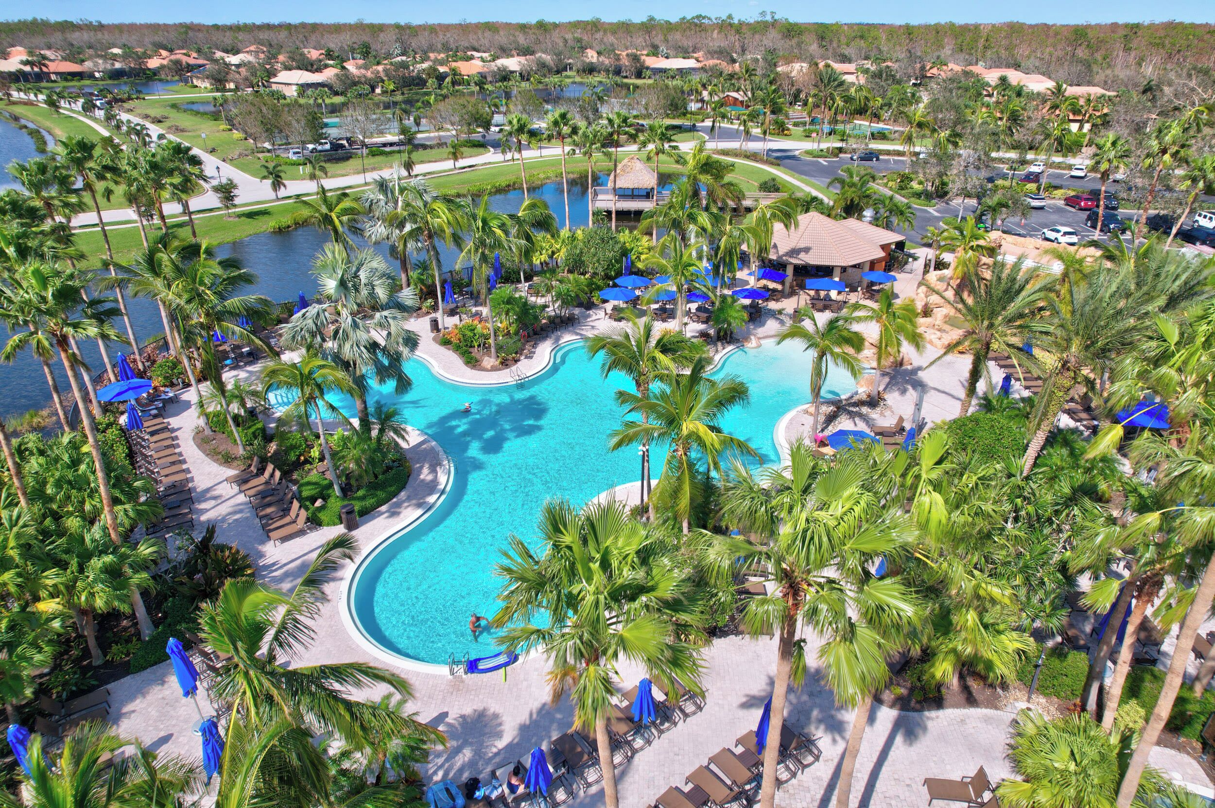 A resort with a large swimming pool surrounded by palm trees and lounge chairs.