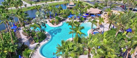 A resort with a large swimming pool surrounded by palm trees and lounge chairs.