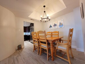 Ein Essbereich mit einem Holztisch, Stühlen, einer Chandelierleuchtre und Bildern an der Wand.