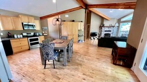 Une cuisine spacieuse avec des meubles en bois, un coin repas avec des chaises à motifs et une cheminée en pierre.