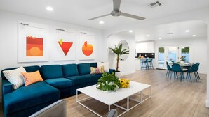 Una sala de estar moderna con un sofá azul, una mesa de centro blanca y un ventilador de techo.