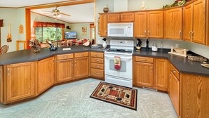 A kitchen with wooden cabinets, a microwave, stove, and a ceiling fan.