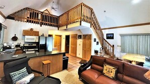 Amplia sala de estar con cocina, escalera y un rincón de estar acogedor.