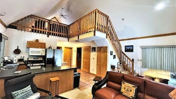 A spacious living area with a kitchen, a staircase, and a cozy seating area.