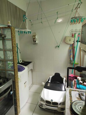 A compact kitchen with a white car in the center, a sink, and various kitchen utensils hanging on the wall. - Charming Apartment in Rio das Ostras (Rio das Ostras)