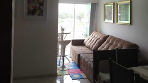 Una sala de estar con un sofá, una mesa de comedor y sillas. Se ve un ventanal con vistas al exterior.