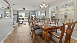 Un comedor con una larga mesa de madera, sillas y una araña.