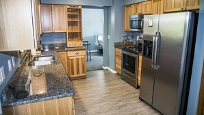 Une cuisine avec des meubles en bois, un réfrigérateur en acier inoxydable et un plan de travail en granit.