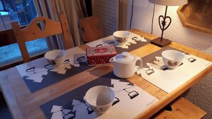 A dining table set with cups, a teapot, and a box, with a window and curtains in the background. - Studio in Front De Neige Charvet Arc 1800 (Les Arcs)