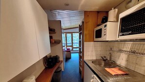 A compact kitchen with a microwave, stove, and sink. There is a window providing natural light and a view of the outdoors. - Studio in Front De Neige Charvet Arc 1800 (Les Arcs)