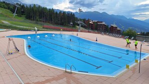 A swimming pool with lanes, a lifeguard, and a view of mountains. - Studio in Front De Neige Charvet Arc 1800 (Les Arcs)