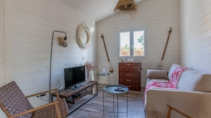 A cozy room with a wooden TV stand, a small round table, a sofa, and a wooden dresser.