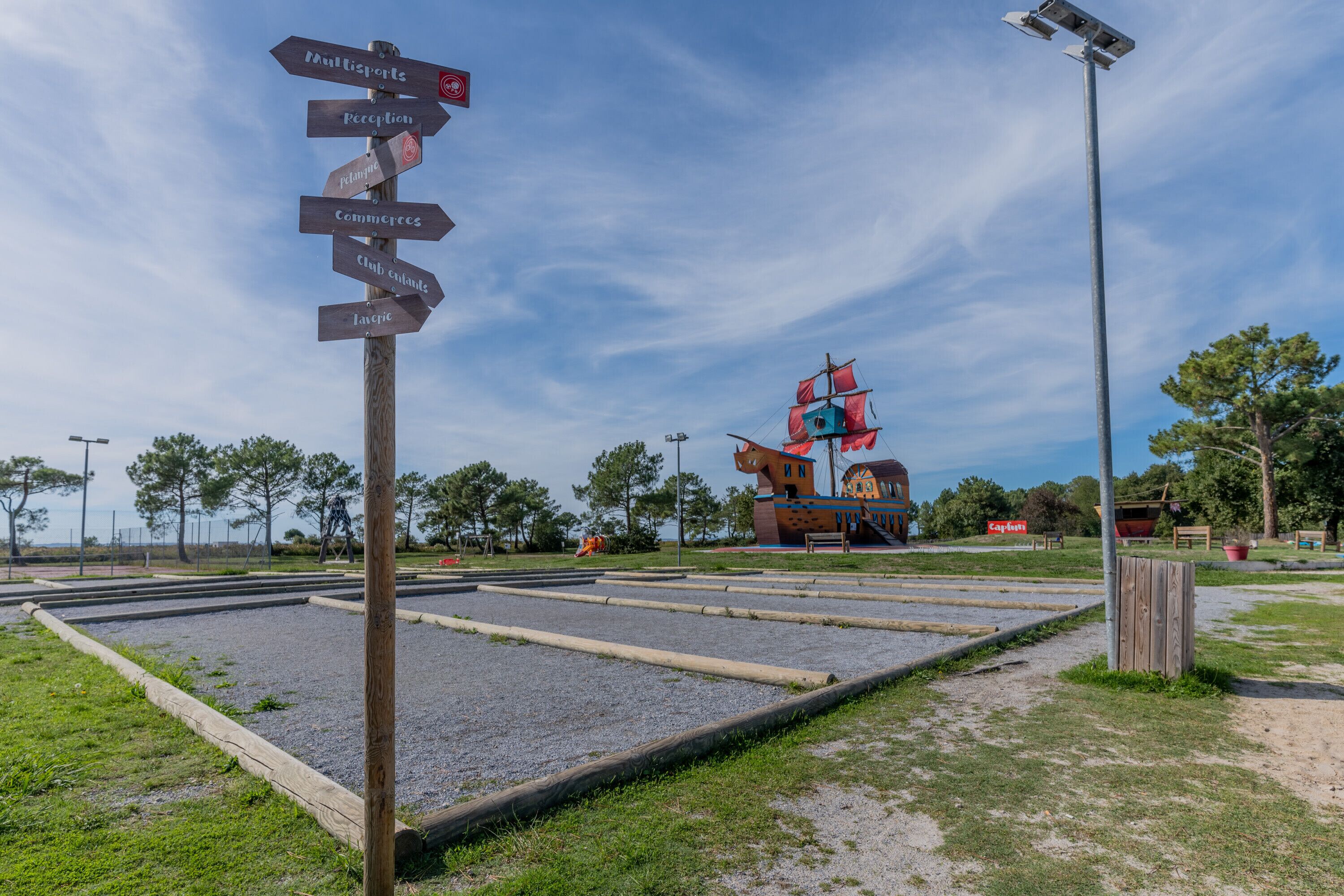A signpost with directions to various facilities, a ship-shaped building, and a clear sky.