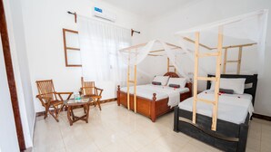 A room with two wooden beds, a wooden table, and two wooden chairs. - Savi House Nungwi (Zanzibar)