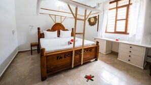 A bedroom with a wooden four-poster bed, a desk, and a window with curtains. - Savi House Nungwi (Zanzibar)