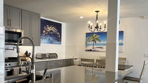 A modern kitchen with a large island, stainless steel appliances, and artwork on the walls.