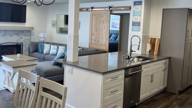 A modern kitchen with a central island, white cabinetry, and a dining area with a table and chairs.