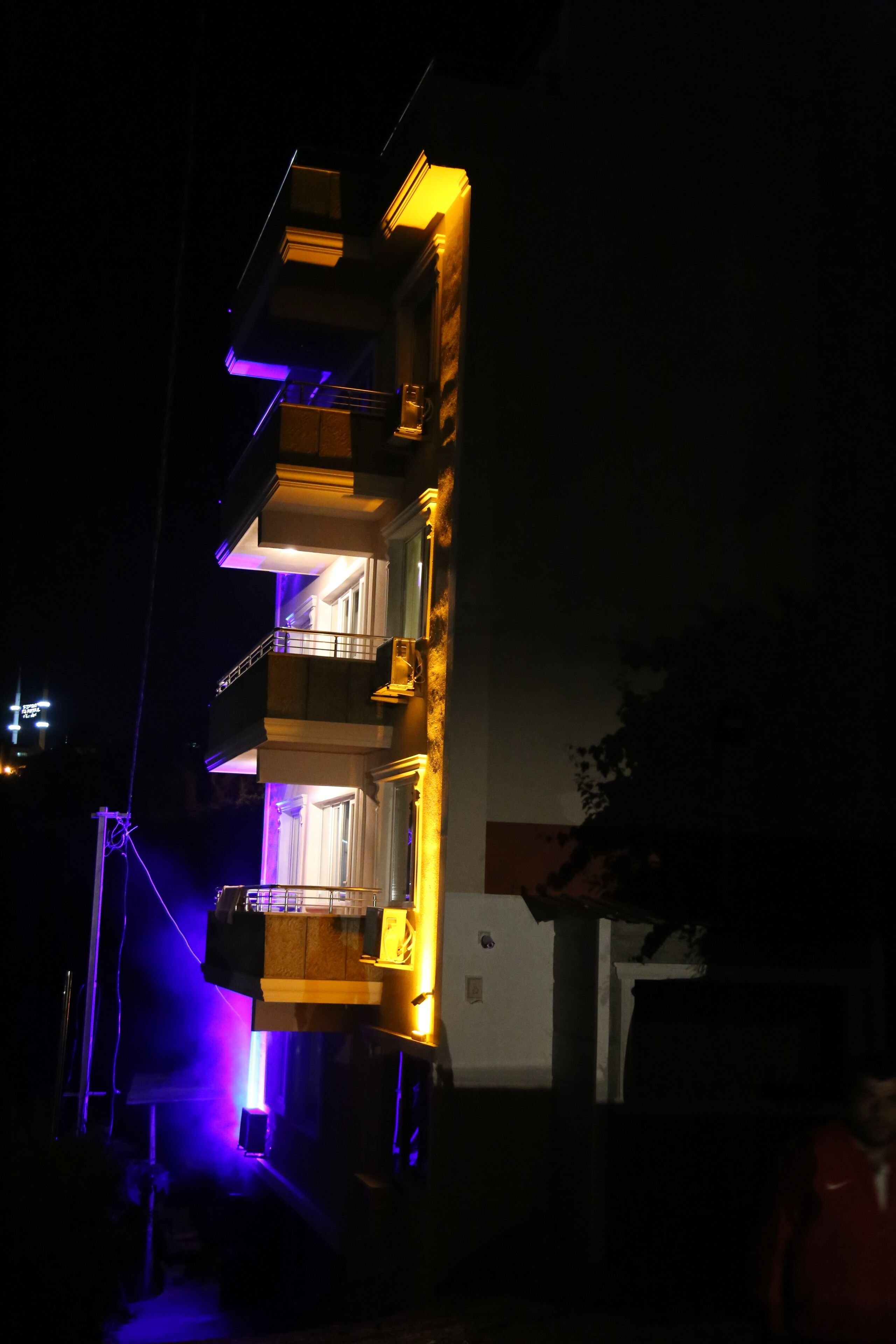 Un edificio de varios pisos con balcones y ventanas iluminadas en la noche.