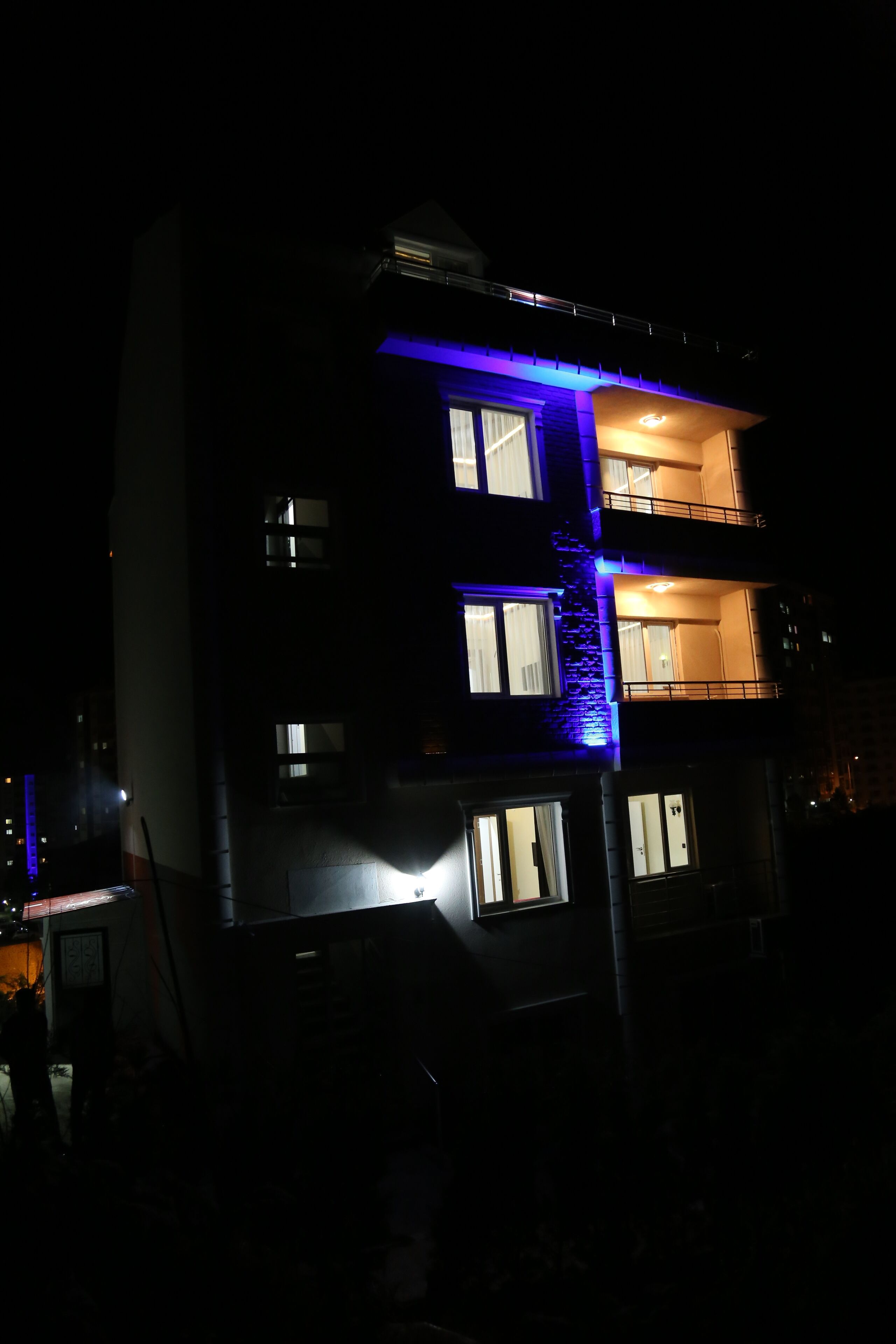 Um edifício com várias andares, varandas e janelas iluminadas à noite.