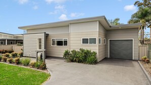Uma casa moderna de dois andares com fachada cinza, uma garagem frontal e um jardim bem cuidado.