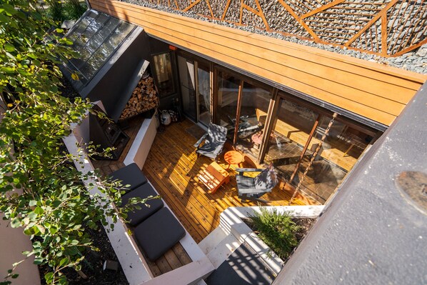 An outdoor deck with wooden flooring, a fire pit, and seating areas.