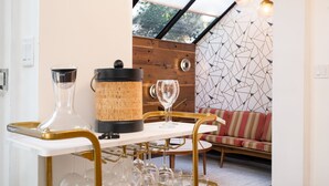A dining area with a white table, gold chairs, and a wooden wall. There are wine glasses and a corked bottle on the table. - Dove's Nest | Unique Earth Home | Decks (Minneapolis)