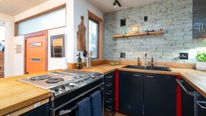 A modern kitchen with a large stove, a sink, and wooden countertops. - Dove's Nest | Unique Earth Home | Decks (Minneapolis)