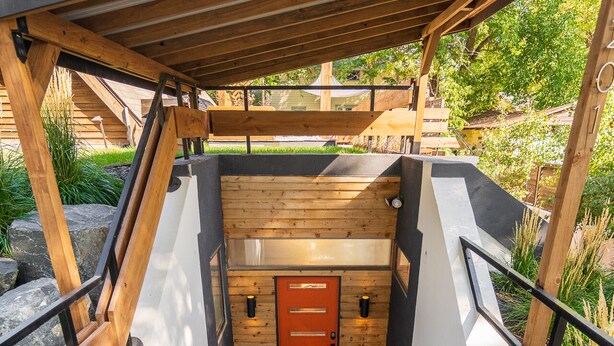 A wooden deck with a door, surrounded by white walls and a black roof. - Dove's Nest | Unique Earth Home | Decks (Minneapolis)