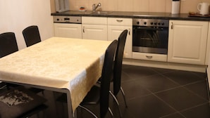 A kitchen with a dining table, chairs, cabinets, a stove, and a sink. - Gruyère-rooms (Gruyeres)