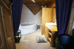 Bathroom features a bathtub, wooden vanity with sink, and small rug.