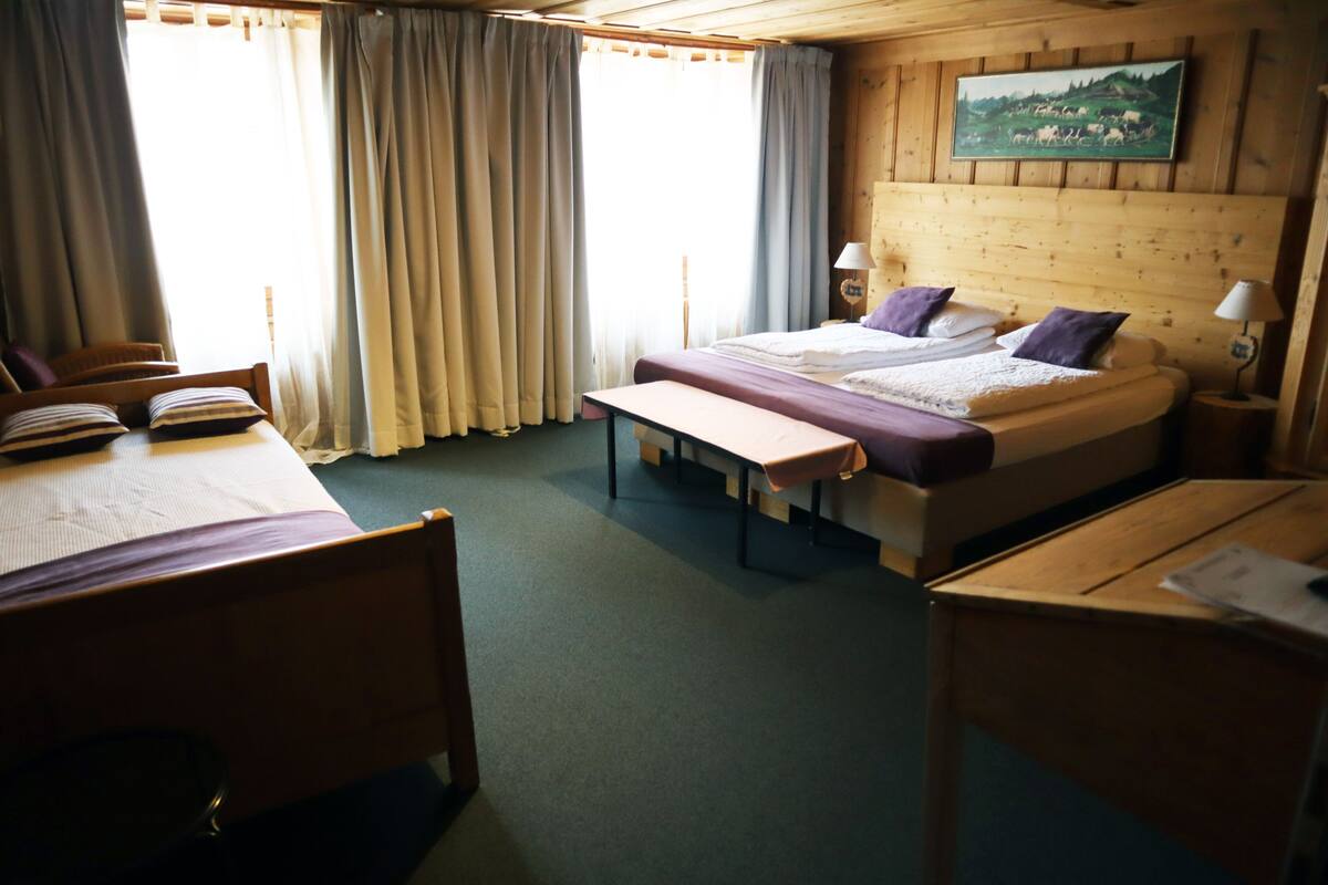 A room with a bed, a desk, a chair, and a bench.