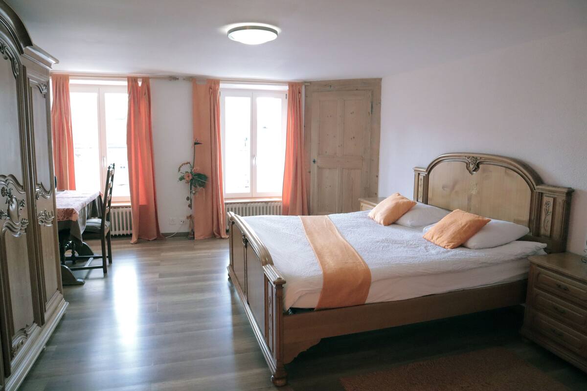 A bedroom with a wooden bed, a nightstand, a dresser, and a chair.