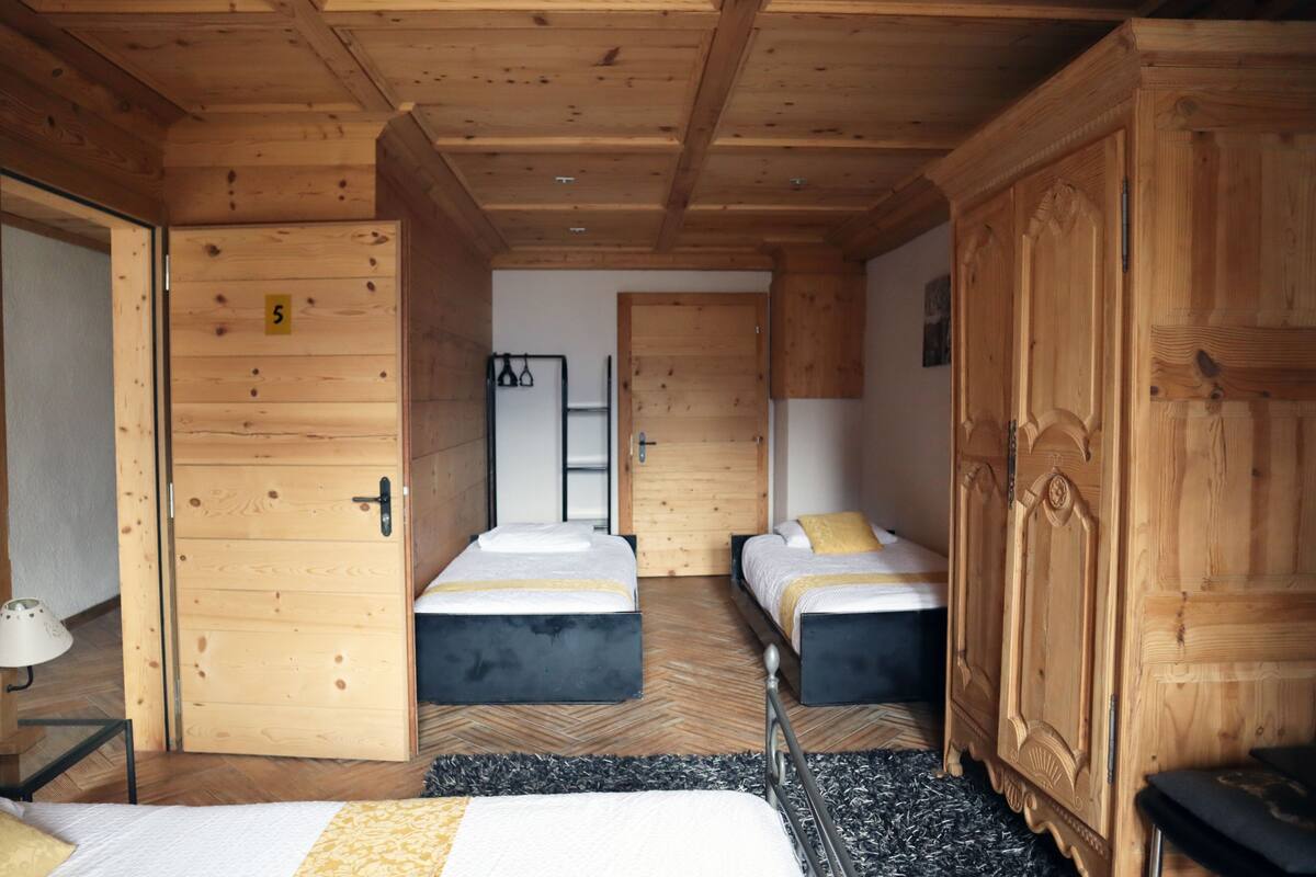 A wooden room with two beds, a wardrobe, and a door marked with the number 5.