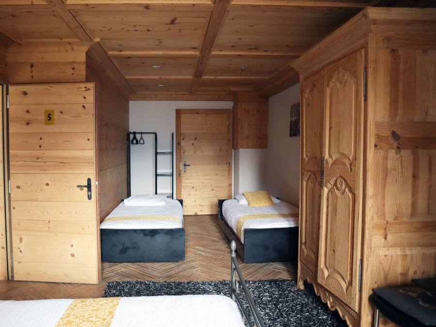Habitación de madera con dos camas, un armario y una puerta marcada con el número 5.