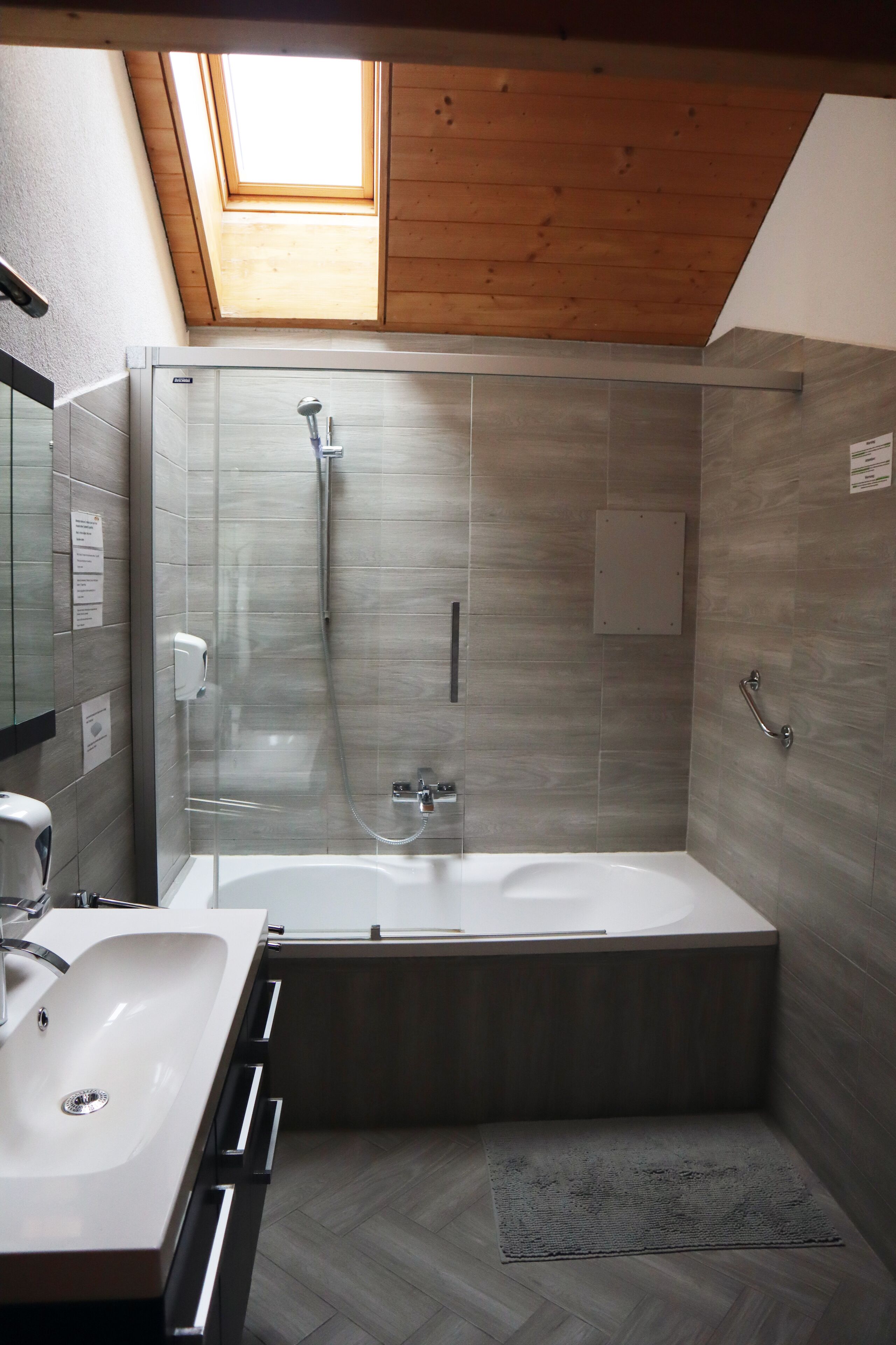 Un baño moderno con tragaluz, bañera, ducha y lavamanos.