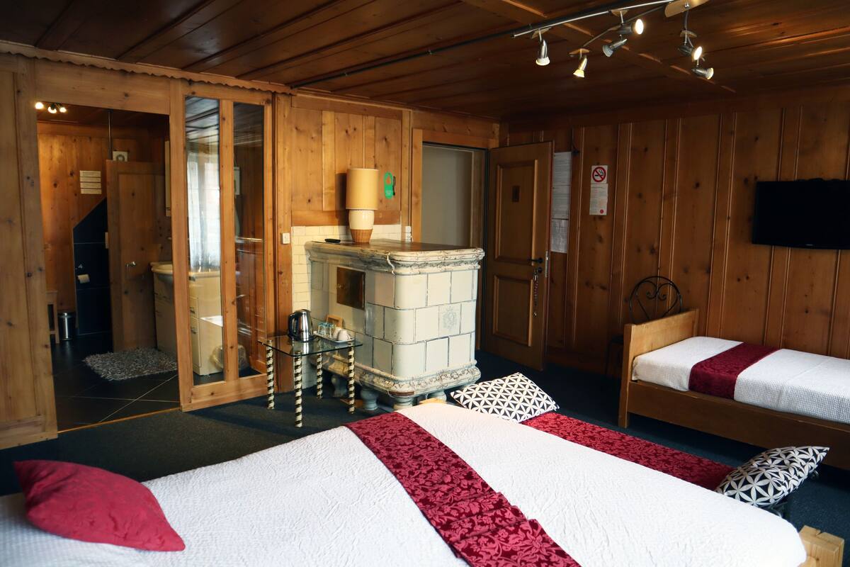 A wooden cabin room with two beds, a fireplace, and a television.