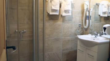 A bathroom with a glass shower enclosure, a sink, a toilet, and a mirror.