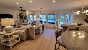 A spacious living area with a wooden dining table, a sofa, and a TV.