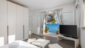 Ein modernes Schlafzimmer mit Bett, Fernseher und Meerblick.