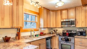 A kitchen with wooden cabinets, a granite countertop, stainless steel appliances, and a window providing natural light. - Tranquil 3BR Home; Access To Trails & Mtn. Views! (Breckenridge)