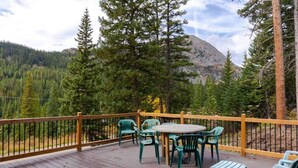 A wooden deck with outdoor seating and a view of a forested mountain. - Tranquil 3BR Home; Access To Trails & Mtn. Views! (Breckenridge)