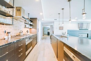A modern kitchen with dark wood cabinets, a granite countertop, and pendant lighting.